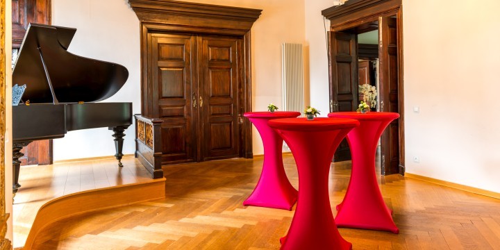 Stehtische mit roten Hussen vor Flügel in der Villa Rosenthal